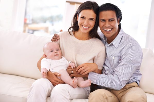 A happy couple holding their gorgeous baby boy and smiling